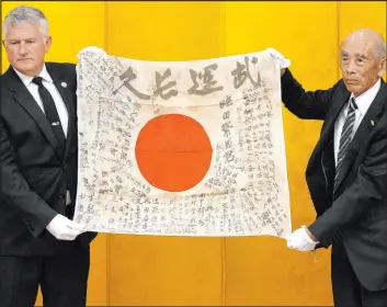  ?? Shuji Kajiyama
The Associated Press ?? USS Lexington Museum executive director Steve Banta, left, and Toshihiro Mutsuda, the elderly son of Japanese soldier Shigeyoshi Mutsuda, hold together Mutsuda’s good luck flag during the handover ceremony Saturday in Tokyo, Japan.