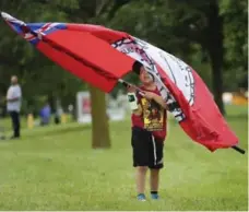 ??  ?? Kayson Bruisedhea­d, 6, from Tsui T’ina nation near Calgary, waves a flag as athletes gather outside of the stadium at York University on Sunday for the beginning of the North American Indigenous Games.