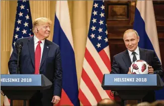  ?? CHRIS MCGRATH / GETTY IMAGES ?? With President Donald Trump looking on, Russian President Vladimir Putin holds a World Cup soccer ball during a joint news conference after their meeting Monday in Helsinki. The two leaders met one-on-one and discussed a range of issues, including the 2016 U.S election.