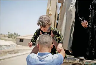  ??  ?? A man assists a girl as displaced civilians arrive at a processing center before being transferre­d to refugee camps in western Mosul on Monday. (Reuters)