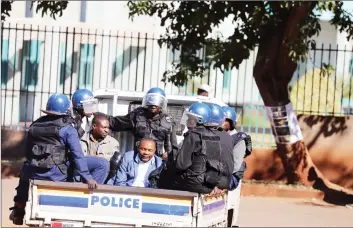  ??  ?? Shadreck Mashayamom­be sits under guard in a police truck yesterday after being arrested in connection with violent demonstrat­ions that rocked Harare on Wednesday