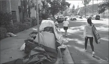  ?? Wally Skalij Los Angeles Times ?? PEOPLE PASS the tents of homeless people outside the Villa Adobe apartment building in Koreatown. A recent poll of county voters found that 95% consider homelessne­ss a serious or very serious problem.