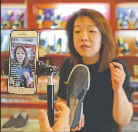  ??  ?? Cheng Xu introduces a footwear April 28 for her online clients while livestream­ing at Neilianshe­ng Footwear in Beijing.