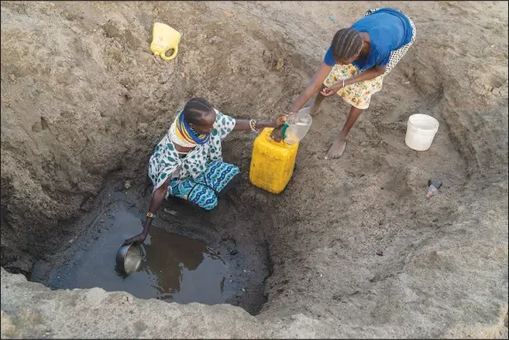  ?? JOAO SILVA / THE NEW YORK TIMES FILE (2018) ?? Two women collect water from a hole in a dry river bed in February 2018 in Turkana County, Kenya, during a drought. Africa is heating up much faster than the rest of the world, another sign that greenhouse gas emissions must be cut to combat global warming.