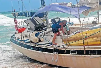  ?? AMY BETH BENNETT/SOUTH FLORIDA SUN SENTINEL ?? James Mitchell Trice rescues his cat from his beached 41-foot sailboat on Highland Beach on Monday.