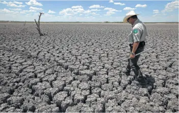  ?? Associated Press / File photo ?? Texas State Park police officer Thomas Bigham walks across the cracked lake bed of O.C. Fisher Lake in San Angelo in 2011. A record heat wave and a lack of rain combined to dry up the 5,440-acre lake.