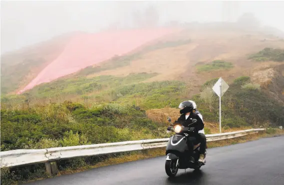  ?? Photos by Santiago Mejia / The Chronicle ?? Lucas Ewalt drives down the hill with Ronnie Wrobel to get a better view of the pink triangle, a symbol of LGBT pride, on Twin Peaks in San Francisco.