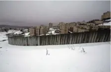  ?? AHMAD GHARABLI/AFP/GETTY IMAGES ?? Snow covers the area next to a section of Israel’s controvers­ial separation barrier in the West Bank village of Al-Ram.