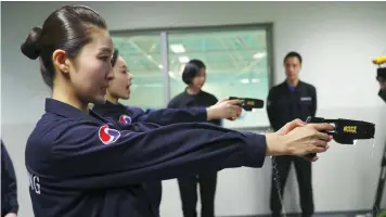  ?? — AFP ?? Crew members of Korean Air using stun guns at a training centre in Seoul.