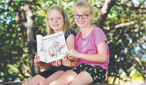  ?? Picture: BRENDAN RADKE ?? NOVEL APPROACH: Twins Jayde and Amber Breed, 9, read Wilfrid Gordon McDonald Partridge, available for $2.70 when purchasing the Cairns Post.