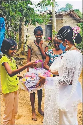  ??  ?? Rasanga hands a packet to a young girl.