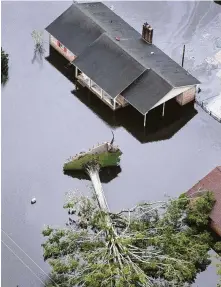  ?? Steve Helber / Associated Press ?? Hurricane Florence uproots a tree and floods nearby homes in New Bern, N.C., where hundreds of people had to be rescued.