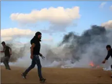  ??  ?? Protesters try to throw back teargas canisters fired by Israeli troops near the fence of the Gaza Strip border with Israel, during a protest east of Khan Younis, southern Gaza Strip, on Friday.
AP Photo/Adel hAnA