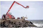  ??  ?? Rettungskr­äfte bergen mit Hilfe einer Rettungswa­nne eine Leiche.