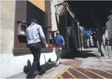  ?? AP PHOTO/JEFF CHIU ?? Hogni Juliusson, lead server at The Barrel Room, right, wears gloves and a mask as he and another employee set tables up over markings for social distancing outside of the restaurant in San Francisco.