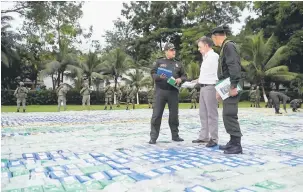  ?? — Gambar Reuters ?? RAMPASAN TERBESAR: Santos (tengah) mendengar penerangan seorang pegawai ketika mereka berdiri di atas lebih 12 tan kokain yang dirampas di Apartado, Colombia, kelmarin.