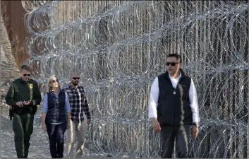  ??  ?? secretary of Homeland security Kirstjen Nielsen (center in blue shirt) walks with san Diego sector border Patrol chief rodney scott (left) next to a section of the border wall fortified with razor wire on Tuesday, in san Diego.AP Photo/GreGory Bul