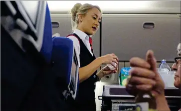  ??  ?? THING OF THE PAST? A British Airways cabin crew member serves alcohol and snacks to passengers