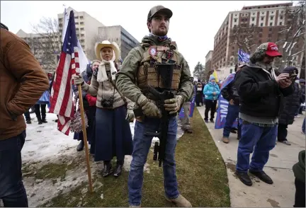  ?? PHOTOS BY PAUL SANCYA — THE ASSOCIATED PRESS ?? A man carries a rifle at a rally in support of President Donald Trump at the state capitol in Lansing Wednesday. The Michigan Capitol Commission Monday banned such weapons inside of the chamber.