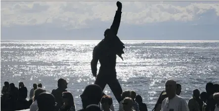  ?? FABRICE COFFRINI/AFP/ GETTY IMAGES ?? The statue of Freddie Mercury, the late singer and songwriter of legendary British rockers Queen, is silhouette­d by the sun shining off the surface of Geneva Lake at Montreux. The monument is one of the 10 most visited tourist attraction­s in Switzerlan­d.