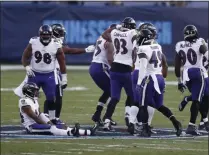  ?? WADE PAYNE - THE ASSOCIATED PRESS ?? Baltimore Ravens players sit and stand on the Tennessee Titans’ logo at the 50- yard line after Ravens cornerback Marcus Peters intercepte­d a pass against the Titans late in the fourth quarter of an NFL wild- card playoff football game Sunday, Jan. 10, 2021, in Nashville, Tenn.
