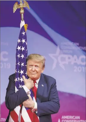  ?? Tasos Katopodis / Getty Images ?? President Donald Trump hugs the U.S. flag during the Conservati­ve Political Action Conference on Saturday in National Harbor, Md.