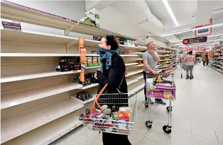  ?? —AFP ?? Shoppers are faced with partially empty shelves at a supermarke­t in London on Saturday, as consumers worry about product shortages, leading to the stockpilin­g of household products due to the outbreak of the novel Covid-19. British Prime Minister Boris Johnson, who has faced criticism for his country’s light touch approach to tackling the Covid-19 outbreak, is preparing to review its approach and ban mass gatherings, according to government sources Saturday.