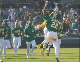  ?? AP PHOTO TONY AVELAR ?? Oakland Athletics’ Ramon Laureano (22) celebrates with Tony Kemp (5) and teammates after two runs scored on a throwing error by Minnesota Twins third baseman Luis Arraez during the 10th inning of a baseball game Wednesday in Oakland, Calif. Laureano safe at first. Oakland won 13-12.