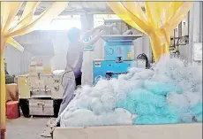  ??  ?? An employee at the Qualy Design factory putting plastic fishing nets into a cutting machine.