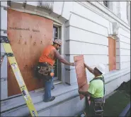  ?? (Wisconsin State Journal/Steve Apps) ?? Troy Richardson (left) and Corey Rockweiler with Daniels Constructi­on board up street level windows near the West Washington entrance to the Capitol in Madison, Wis.