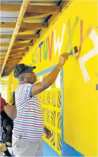  ?? ?? Assistant Commission­er of Police Calvin Allen, head of the Police Area 2, repaints the alphabet on the walls of the basic school.