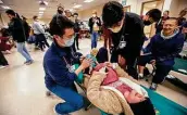  ?? Michael Miller / Bryan-college Station Eagle ?? Texas A&M medical student Andrew Wang, left, and Timothy Fan present her “newborn” to “survivor” Dominique Paderin during a disaster drill Friday.