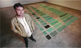  ?? Mark Mulligan / Houston Chronicle ?? Houston artist Gabriel Martinez poses with his piece “The Long Poem of Walking,” a collection of broken automotive glass he has found moving through the city, which is at the center of his first solo museum exhibition at the Blaffer Art Museum.