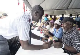  ?? PHOTOS BY GLADSTONE TAYLOR/PHOTOGRAPH­ER ?? Salvation Army Commission­er Devon Haughton (left) greets and serves a meal to Jusiah Barrett at the Food For The Poor annual Christmas treat for more than 3,000 indigent persons at Emmett Park in Kingston yesterday.