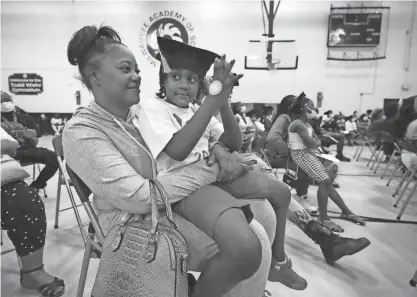  ?? PHOTOS BY MIKE DE SISTI / MILWAUKEE JOURNAL SENTINEL ?? Milwaukee Academy of Science rising first grader Nathaniel Logan claps while sitting on the lap of his mother, Ayanna Taylor, as they get the news of the “I Have A Dream” scholarshi­p program during a K-5 promotion ceremony Thursday.