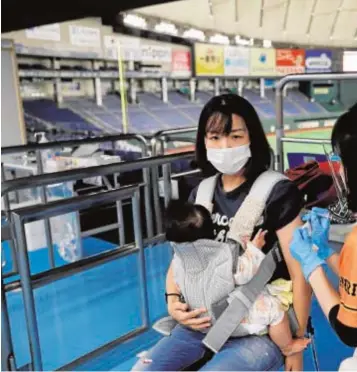  ?? // REUTERS ?? Una joven madre se vacuna en un estadio de béisbol en Tokio