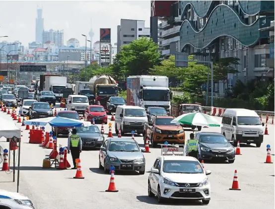  ?? — LOW BOON TAT/ TheStar ?? A police roadblock at the Sungai Besi toll plaza. Nearly 150 such roadblocks have been set up nationwide to monitor motorists travelling interstate during the conditiona­l movement control order period.