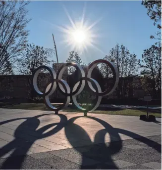  ?? CARL COURT/ GETTY IMAGES ?? The Olympic rings cast a shadow in Tokyo on Tuesday, the day the Internatio­nal Olympic Committee and Japanese government announced that the 2020 Olympics will be postponed “to a date beyond 2020 but not later than summer 2021.”
