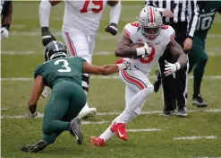  ?? AP Photo/Al Goldis ?? ■ Ohio State's Trey Sermon, right, rushes against Michigan State's Xavier Henderson (3) during the first half of an NCAA college football game Saturday in East Lansing, Mich. Ohio State won 52-12.