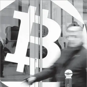  ?? Chesnot Getty Images ?? A MAN walks past the bitcoin symbol on a window of the offices of the bank La Maison du Bitcoin in Paris. The value of bitcoin shot past $16,000 apiece Thursday, up from about $1,000 at the start of 2017.