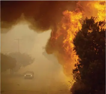  ?? PHOTO AFP ?? Un véhicule des pompiers passe près des flammes de l’incendie « Thomas » qui continuait de progresser, hier, en dépit des efforts de 4000 combattant­s du feu mobilisés.