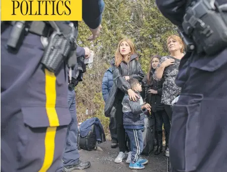  ?? GEOFF ROBINS / AFP / GETTY IMAGES ?? An extended family of eight people from Colombia are detained by RCMP officers after they illegally crossed the border near Hemmingfor­d, Que. Canada has seen an increase in the number of refugee claimants walking across the border from the United...