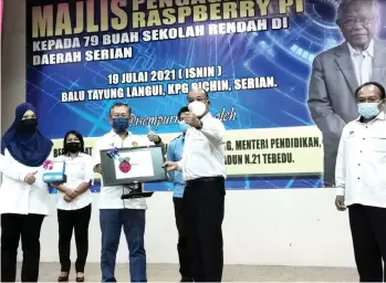  ??  ?? Martin (third left) on behalf of Manyin performs the symbolic handing-over of the device to Charlie. Also in the photo is Azizah (left).