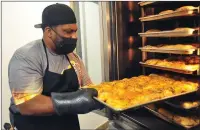  ?? Photo by Ernest A. Brown ?? Jermaine Robinson, owner of Bugg’d Outt BBQ in Woonsocket, checks on the baked chicken he is preparing at Millrace Kitchen Friday afternoon for this year’s J.W. Hinson Scholarshi­p Banquet, hosted by Woonsocket’s MLK Community Committee Friday evening. The event was catered this year due to the coronaviru­s pandemic.