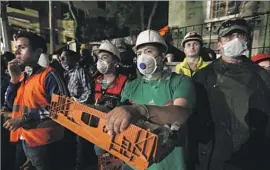  ??  ?? PEOPLE await news as search and rescue crews toil away. Cheers erupted at the site of an office building where three people were pulled alive from the rubble.