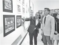  ??  ?? ROSMADI (kiri) menunjukka­n hasil lukisan mendiang Francis Cheong pada majlis penutupan itu.