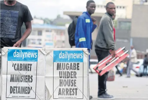  ??  ?? UNCERTAINT­Y: People pass newspaper billboards in Harare on Thursday. President Robert Mugabe’s decades-long rule seems to be over after a military coup.