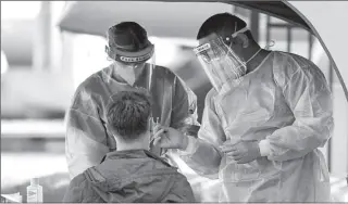  ?? SYDNEY
- REUTERS ?? Medical personnel administer tests for the coronaviru­s disease Sydney, Australia.
( COVID- 19) at a pop- up testing centre in