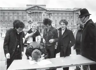  ?? PA via AP, File ?? ■ British group, the Sex Pistols, sign a new recording contract with A&M Records outside Buckingham Palace in London, 1977. In Britain, there are several traditiona­l elements to a royal anniversar­y: pageants, street parties, the Sex Pistols. Queen Elizabeth II and the Pistols have been linked since the punk pioneers released the song “God Save the Queen” in 1977 during the monarch’s Silver Jubilee. The anti-authoritar­ian anthem has been re-released to mark the queen’s Platinum Jubilee, 70 years on the throne.