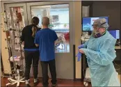  ?? ANDREW SELSKY — THE ASSOCIATED PRESS FILE ?? Two visitors peer into the room of a COVID-19 patient in the intensive care unit at Salem Hospital in Salem, Ore., as a nurse dons full protective gear before going into the room of another patient.